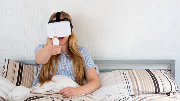 Mulher bonita usando fone de ouvido VR na cama — Fotografia de Stock