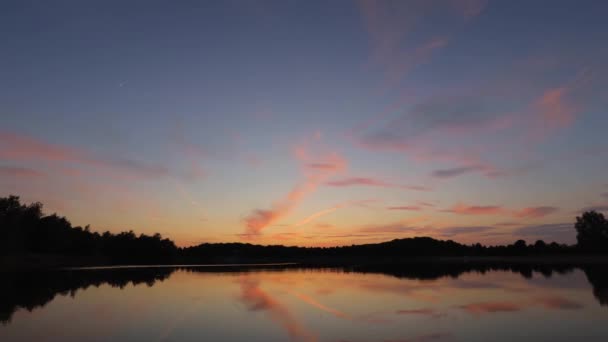 Tiden förfaller med en ung måne och orange solnedgång över spegelytan av sjön — Stockvideo