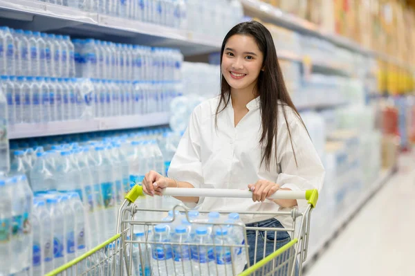 Gülümseyen mutlu kadın süpermarketten alışveriş yapıyor. Genç kadın süpermarketten alışveriş yapıyor.