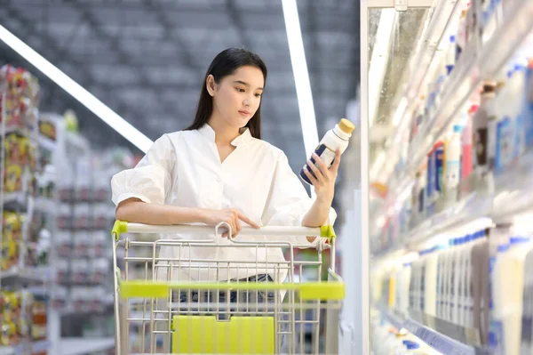 Gülümseyen mutlu kadın süpermarketten alışveriş yapıyor. Genç kadın süpermarketten alışveriş yapıyor.