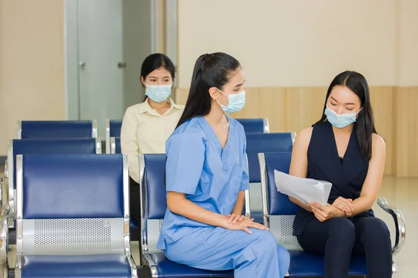 The female medical staff is presenting a treatment plan for the patient while sitting in the hospital reception area. The doctor is notifying the patient\'s medical expenses.