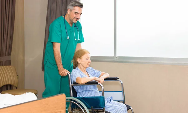 Healthcare worker is helping to push a wheelchair for elderly patients.