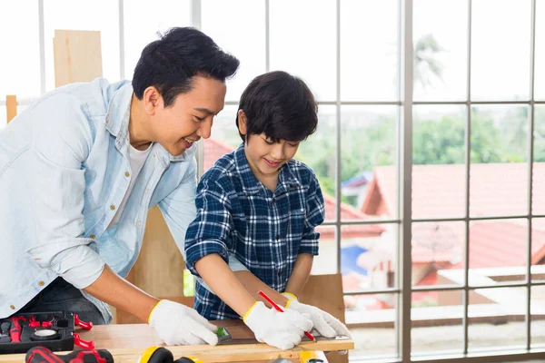 Father and son work together to do woodwork.