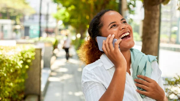 An African American woman is cheerful on the phone.