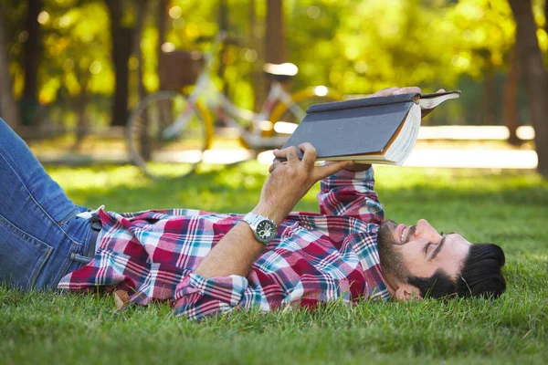 Bahçede Uzanmış Kitap Okuyan Yakışıklı Adam Dinleniyor — Stok fotoğraf