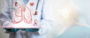 Akciğer hastalığı tedavisi kavramı. Bir doktorun elinde akciğer ikonunu gösteren bir tablet var. Arka planda da göğüs cerrahisinin ışıkla bulanık bir resmi var..