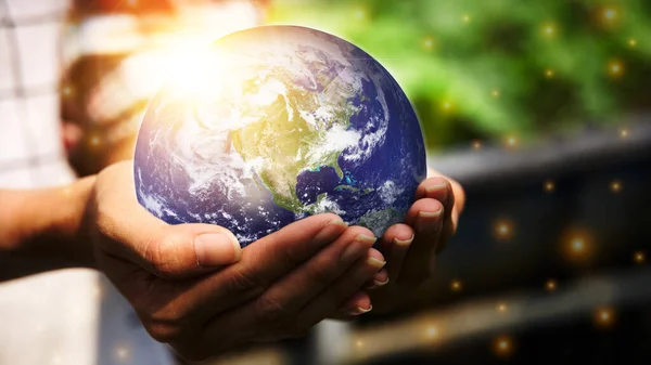 A woman\'s hand was holding a globe and there is an orange light spot. Environment concept and world guardian organization. Earth image courtesy of NASA.