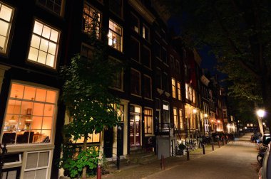 Amsterdam 'da gece, sokak lambalarının ışığında bisiklet ve caddeler. Gece. 