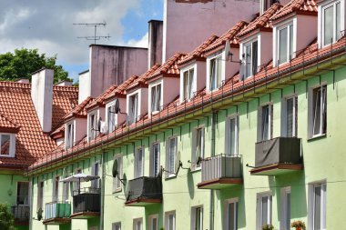 Güneşli bir günde balkonları ve kırmızı çatısı olan çok ailelik bir ev. Yaz.