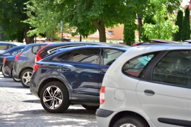 Güneşli bir günde cadde boyunca park edilmiş arabalar ve araçlar. Yaz.