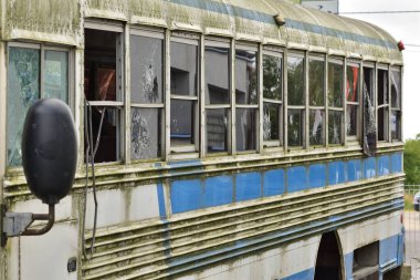 Uzak bir bölgede kırık camlı harap ve paslı bir otobüs.