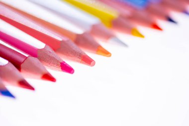 Beyaz arka planda 24 renkli boya kalemi, düzgün düzenlenmiş ve sivriltilmiş. Merhaba okul.