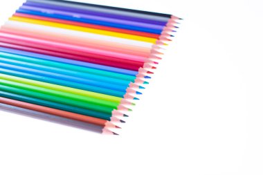 Beyaz arka planda 24 renkli boya kalemi, düzgün düzenlenmiş ve sivriltilmiş. Merhaba okul.