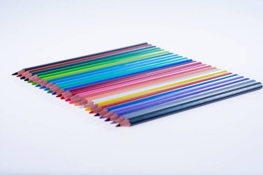 Beyaz arka planda 24 renkli boya kalemi, düzgün düzenlenmiş ve sivriltilmiş. Merhaba okul.