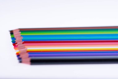 Beyaz arka planda 24 renkli boya kalemi, düzgün düzenlenmiş ve sivriltilmiş. Merhaba okul.