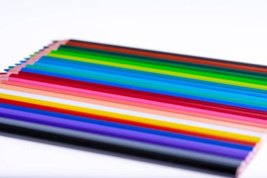 Beyaz arka planda 24 renkli boya kalemi, düzgün düzenlenmiş ve sivriltilmiş. Merhaba okul.