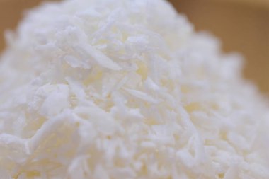 Tahta bir kasede hindistan cevizi talaşı, beyaz bir arka planda..