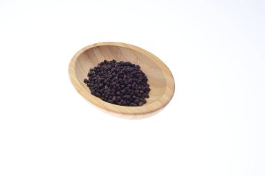 Beyaz arka planda ahşap bir kasede siyah biber. Yiyecek..