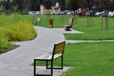 Bulutlu bir günde yaya yolu kenarında park bankında. Dinlen..