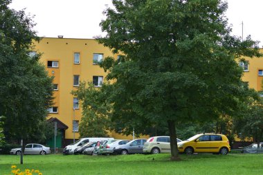 Apartman blokları, otoparkta arabalar ve bulutlu bir günde ağaçlar. Yaşamak için.