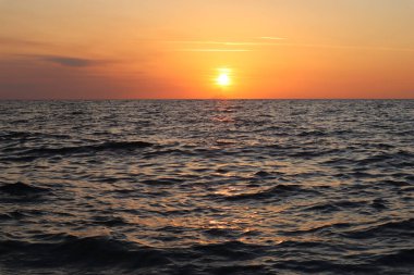 Deniz manzaralı günbatımı ve ufuk çizgisinde Stromboli Adası silueti, Calabria, İtalya. Parlak turuncu gökyüzü, gün batımında bulutlar ve güneş, ufukta bir volkanın silueti, sonbahar akşamında deniz yüzeyinde parlayan güneş.