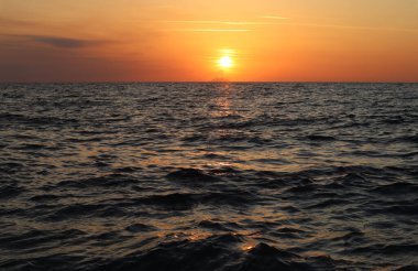 Deniz manzaralı gün batımı, İtalya 'nın Calabria kentindeki Stromboli adasının bulutları ve siluetinde güneş. Gün batımında parlak güneş, bir volkanın silueti ve ufuktaki bulutlar, güneş ışınlarıyla aydınlatılmış, deniz yüzeyindeki dalgalar
