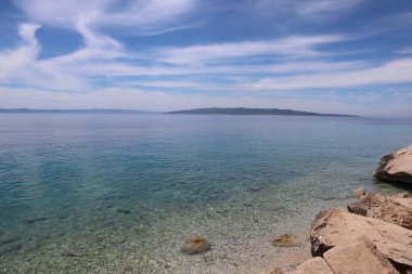Hırvatistan 'da güneşli bir yaz gününde bulutlu mavi gökyüzü ve deniz manzarası