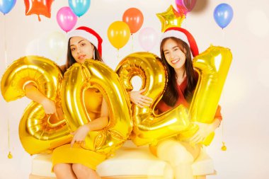 Asyalı kızlar Mutlu Yıllar ve Noel partisi elbisesi elinde altın numaralı balon, 2021, yeni yıl tatili fotoğraf stüdyosu konsepti