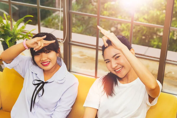 Concept communication using sign language : The fun, companionship of two Asian women using sign language to express greetings instead of informal words in the living room.