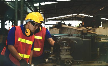 Metal dönüşümlü makineler üzerinde çalışan profesyonel teknisyenlerin ekip çalışması ve görevlerinin bölünmesi ve güvenlik için koruyucu ekipmanlar yerleştirildi.