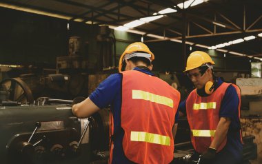 Takım çalışması kavramı: Profesyonel metal fabrikası teknisyenlerinin ortak takım çalışması makineleri çalışanları güvenli, sağlıklı ve iyi iş kalitesinde tutmak için verimli bir şekilde çalışır.