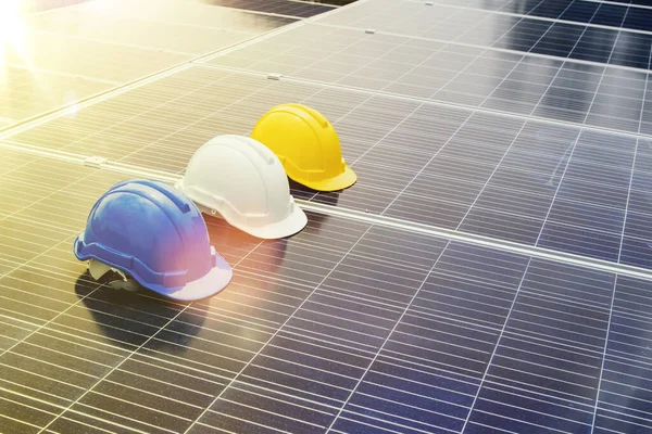 Concept safe operation : White, blue and yellow safety helmets for engineers, architects and workers on solar panels, solar power generation, renewable energy and industrial ecology.