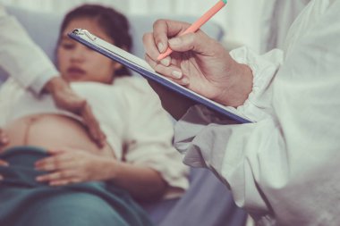Yakın plan, hastanede uzman bir kadın doğum uzmanı tarafından muayene edilen hamile kadınların gelişimine ait bir not..
