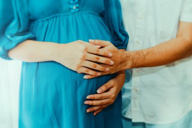 Kadının eli kocanın elinin üstüne konur, rahmin nazik bir dokunuşunu paylaşır, fetüse duyulan sevginin bir göstergesi olarak..