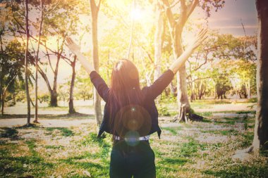 Pozitif enerji kavramına bakın: Uzun saçlı bir iş kadınının arka görünüşü ellerini kaldırdı, doğal yeşillik ve temiz havayla canlandı ve başarılı bir başlangıç için ilham verdi..