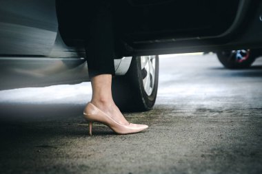 Kahverengi topuklu ayakkabı giyen iş kadını, her gün seyahat etmek için doğru adım atmak üzere arabasının kapısını açtı..