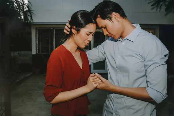 Concept house sales and relocation : Couples stand in front of the house holding hands in sorrow and mourning because they want to sell their house and move out of their former home.