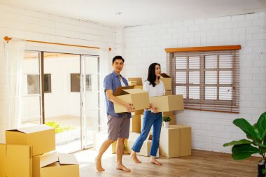 Mutlu taşınma günlerini ve aile için yeni bir hayata başlamayı düşünün: Asyalı çift, birlikte, bir karton kutu tutarak, neşe içinde yeni evlerine yürüdüler.