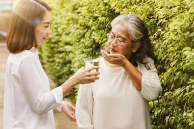 Kız, ilaç ve içme suyu vererek yaşlı anneye baktı. Kız, annesine iyi dileklerle minnettar kaldı ve ona iyi dileklerle baktı: yaşlılar için sağlık hizmeti kavramı ve hayat sigortası.