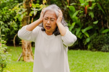 60 'lı yaşlardaki yaşlı Asyalı kadın şiddetli bir baş ağrısı çekiyordu, baş ağrısı çekiyordu ve çok sabırlıydı: sağlık sorunları kavramı, yaşlılar için sağlık hizmetleri.