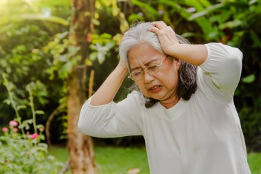 60 'lı yaşlardaki yaşlı Asyalı kadın şiddetli bir baş ağrısı çekiyordu, baş ağrısı çekiyordu ve çok sabırlıydı: sağlık sorunları kavramı, yaşlılar için sağlık hizmetleri.