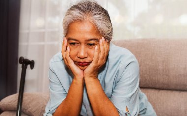 Yaşlılar için sağlık sigortası kavramı: mutsuz, yaşlı bir kadın yalnız başına oturmuş, sağlığını ve hastalığını düşünüyordu: Yaşlı kadın, sağlık sorunları yüzünden stresli ve bunalımda..