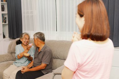 İyi aile ilişkileri birbirini sever ve ilgilenir: Kız ayakta durur ve yaşlı babaya tatlı yediren anneye bakar..