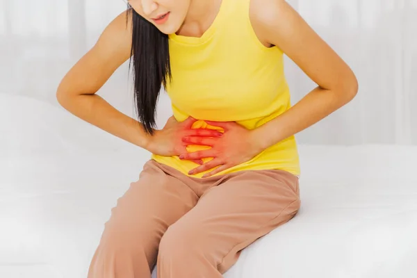 Women with abdominal pain and health care concept : Asian women sit in bed with abdominal pain, abnormal abdominal organs, possibly menstruation.Severe pain is a warning sign of uterine abnormalities.