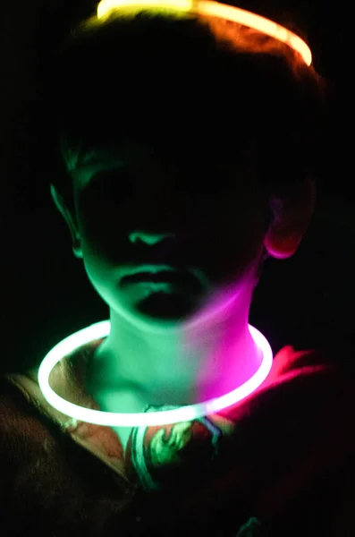 A boy playing with glow sticks in lowlight conditions