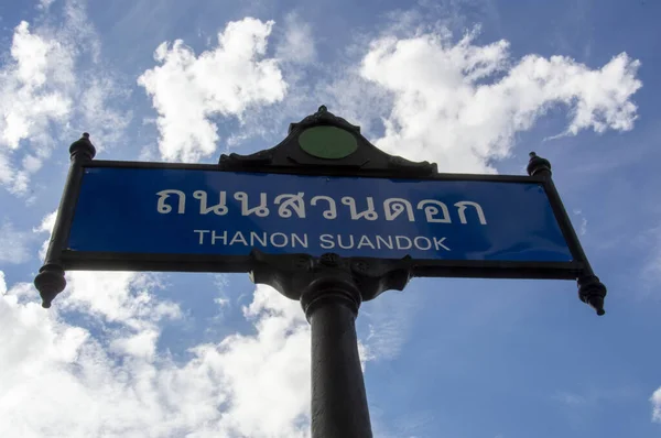 A pole of a city street sign with a sky in the background.