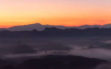 Kompleks dağların manzara görüntüleri sabah sislerin arasından süzülürken güneş ufuk çizgisinden yükselmeye başladı, seyahat kavramı için güzel doğa arka planı..