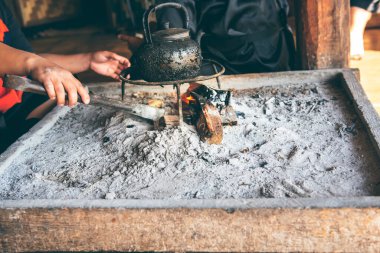 Ahşap yakıt çubuklarından siyah ve kirli lekeler taşıyan su ısıtıcısı kullanan insanlar kürsüde, kül dolu ahşap bir kutunun içinde, yanıklardan doğal yakıt kavramına kadar..