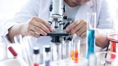 Bilim adamının iş yerinde bilim konseptine uygun kaliteyi elde etmek için mikroskop kullanarak ürün teftişi yaparken bulanık görüntüleri..