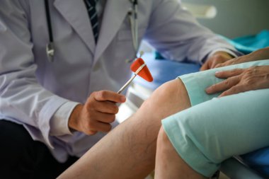 Diz bölgesinde Trigonal Kafa Nörolojik Vurmalı Çekiç kullanan doktor, hastanın sinir sistemini kontrol etmek için, hastalığı teşhis etmek için,